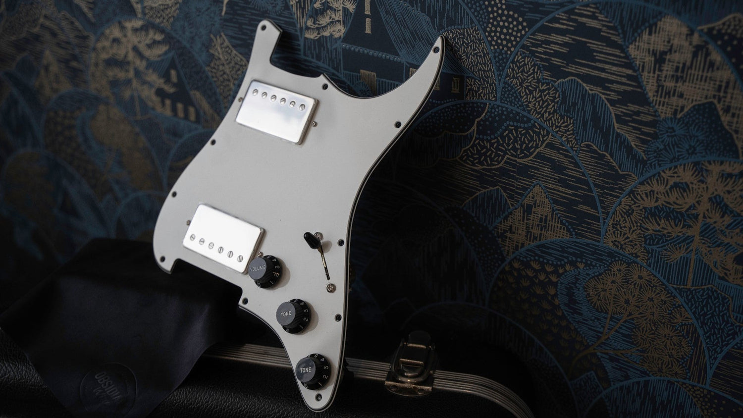 An obsidianwire loaded pickguard for Stratoaster in mint green, with aged white pickup covers in knobs.